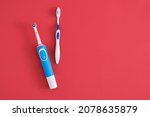 Small photo of different toothbrushes on red background, electric toothbrush or plastic toothbrush, environmental friendliness lifestyle concept, efficiency of brushing teeth