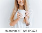 young beautiful girl drinking morning coffee from a large white Cup, posing in front of a white wall, smiling, morning outdoor portrait