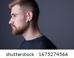 Small photo of Closeup portrait of a young bearded guy of twenty-five years old, standing in profile. In wireless white headphones. Sporty style. Athletes headphone promotional photo