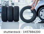 Small photo of 4 new tires that change tires in the auto repair service center, blurred background, the background is a new car in the stock blur for the industry, a four-wheeled tire set at a large warehouse