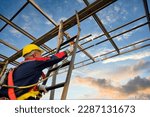 Small photo of Asian male construction worker working at height on steel frame Wear safety gear and safety harness to work at high heights at the construction site.