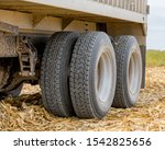 Small photo of Large grain truck with tandem axle dual wheels with retread rubber tires parked in corn field during harvest season. Concept of vehicle maintenance and farm safety checks