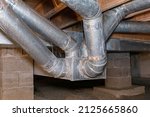 HVAC ductwork, air duct, in crawlspace of house. Duct cleaning, furnace repair and home maintenance concept.