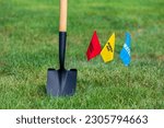 Small photo of Buried electric, natural gas and water utility warning flag with shovel. Notify utility locate company for underground utilities, call before you dig and digging safety concept