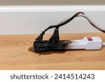 Small photo of Electrical surge protector outlet and extension cord fire. Electricity safety, fire hazard and circuit overload concept.
