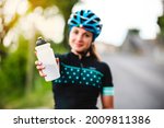 The cyclist holds the water bottle in her hand. Sports water bottle. The beautiful girl at thirst.sport, drinking, water bottle