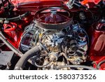 red classic muscle car under the hood, v8 engine with big chromed round air intake filter, tubes, wires, pipes, mechanical and electrical other parts