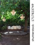 Small photo of Elegant sofa in the garden, outdoor decorative composition with three chandeliers. Beautiful elegant decor for wedding ceremony in beautiful garden. Gazebo for relaxing outdoors. Romantic alcove