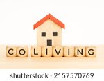 Small photo of Coliving concept. Sharing economy Communal co-living. Wooden blocks with text and house model