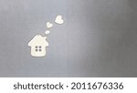 Small photo of Toy wooden house with hearts flying out of the pipe. The concept of the world of love and good neighborliness. Sweet home concept.