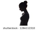 profile silhouette of a pensive girl, a young sad woman lowered her head down on a white isolated background