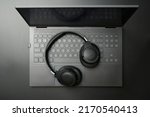Headphones and laptop computer on black desktop. Listening to music, audio, sound concept.
