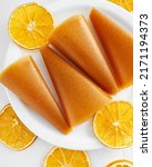 Small photo of Pastille orange rolls. Fruit leather in slices (pastila). Raw food, vegan sweetness, dessert without sugar and flour. Colorful fruit leather rolls on white background with dried orange slices.