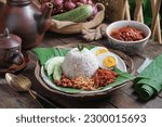 Small photo of Asian food Nasi Lemak is a rice dish infused with coconut milk. Served with sambal, fried anchovies, fried peanut, boiled eggs, and fresh cucumber.