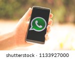 Holding a phone in hand with the WhatsApp app logo shown on screen