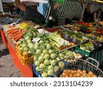Small photo of Flensburg, Germany - May 27 2023: view of a Saturday market stall with fresh assorted vegetables and roots, kohlrabi, onion, carrot and sellers