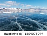 Winter landscape of frozen lake Baikal on a sunny February day. Beautiful blue smooth ice with cracks in the Small Sea Strait. Ice travel in winter holidays. Natural background (focus on ice) 