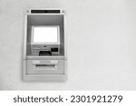 Silver automatic teller machine hanging on a gray concrete wall