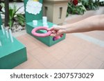 Small photo of Hand holding a red rubber ring for throwing rings in throwing rings where players can throw green and blue rings into a white stick. Players help each other to throw as many rubber rings down the pole