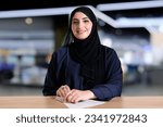 Small photo of Real Emirati Arab woman indoors ideal for corporate banking or office counter table. Arabic Emarat national on Hijab Abaya