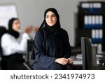 Small photo of Sitting Arab Emirati woman at office with Arabic colleagues, around looking far away. Arabic employee wearing Hijab Abaya.