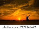 The silhouette of the mill at sunset. Windmill at sunset. Windmill sunset silhouette. Mill at sunset