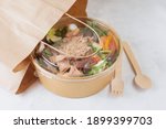 Fish diet salad with tuna, tomatoes, arugula on light background. Healthy vegetarian lunch. Concept eco restaurant delivery, environment protection. Take away food in brown paper craft plate. 