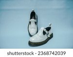 Small photo of Details of casual women's shoes, full white Mary Jane slip on shoes with rubber outsole made from genuine cowhide leather with a neat pattern made by a shoemaker with a turquoise background