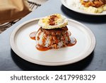 Small photo of A plate of loco moco, white rice topped with beef meat patty, sunny side up egg, and brown sauce.