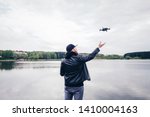 Man operating / flying with drone by the river. Back view shot 