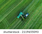 Small photo of Cutting grass silage at field. Forage harvester on grass cutting for silage in field. Self-propelled Harvester on Hay making for cattle at farm. Tractor with trailer transports hay and grass silage.