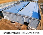 Small photo of Warehouse Construction from metal structure. Industrial building on light gauge steel framing. Frame of modern hangar or factory. Construction site with steel structure warehouse. Top view on a roof.