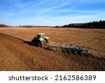 Small photo of Tractor plowing field. Tractor plow soil cultivating. Cultivated land and soil tillage. Agricultural tractor on farm field cultivation. Tractor disk harrow plowing farm field. Agronomy and agrarian.