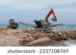 Small photo of Processing stones for beach reconstruction. Jaw crusher on stone crushing at beach. Concrete recycling shredding machine. Shore protection and Beach regeneration. Replenishment of sand on beach.