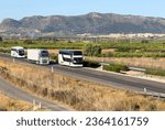 Small photo of Semi truck and Tour Bus driving along highway. Goods Delivery by roads. Services and Transport logistics. Road traffic on motorway. Passenger bus on road. Bus travel in Europe.