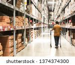 Man in brown t-shirts, cart To buy furniture in the warehouse store.has defocussed and blurred background.