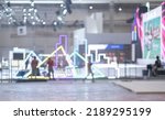 Small photo of Blurry workers preparing exhibition event hall. Bokeh background of trade show business, world or international expo showcase, tech fair, with exhibitor trade show booth displaying product.