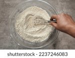 Small photo of A bowl with flour and other dry baking ingredients being mixed with a whisk. Combining dry baking ingredients together.