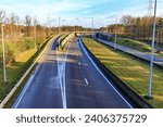 Small photo of Aerial view of side lane in direction to joining a highway road with two lanes, dual carriageways in both directions, bridge and trees in background, autumn day in Limburg province, Belgium