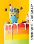 Small photo of KYIV, UKRAINE - December 16: Homemade cake with multicolored rainbow chocolate frosting. Figurine in the shape of minion. Character of the animated movie ''Despicable Me'' on top of the birthday cake