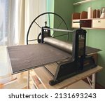 Small photo of Etching press ancient engraving old machine for printmaking. Art equipment in studio. Space for text. Linocut, woodcut, etching, monotype, print, embossing, stamp art printing step process hand made
