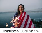 Beautiful woman holding American flag celebrating holding sparkles