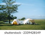 Small photo of White tent and tarp next to a pond with green grass and trees and blue sky with clouds, it's golden hour in the morning vibes in luxury camping or glamping