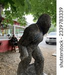 Small photo of Hiouchi, CA, USA - July 12, 2023 - a young man sits and gazes in amusement at a Bigfoot statue near the redwood forest in Northern California