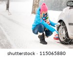 Woman putting winter tire chains on car wheel snow breakdown