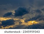 Small photo of A dramatic photo of a cloudy sky with the sun shining through the clouds. The clouds are dark and foreboding, but the sun's rays create a sense of hope and optimism.