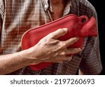 Small photo of Asian elder man suffering from central chest pain. Caused by heart attack, myocardial infarct or ischemia, myocarditis, pneumonia, oesophagitis, stress, etc.Therapy by rubber hot water bag.