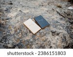 Small photo of Closeup of a set of romantic his and hers vow booklets with paper filled with intimate wedding vows lays on mossy rocky ground in Rocky Mountain National Park Colorado waiting for adventure elopement