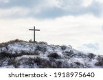 Wooden cross on the mountain covered with white snow in winter, Symbol of God loved to people on the hill, The Christian cross seen as a representation of the instrument of the crucifixion of Jesus.