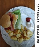 Small photo of A bacon hamburger on a beautiful plate. The side dish is baked potatoes. Furthermore there are dips, mayonnaise and ketchup.